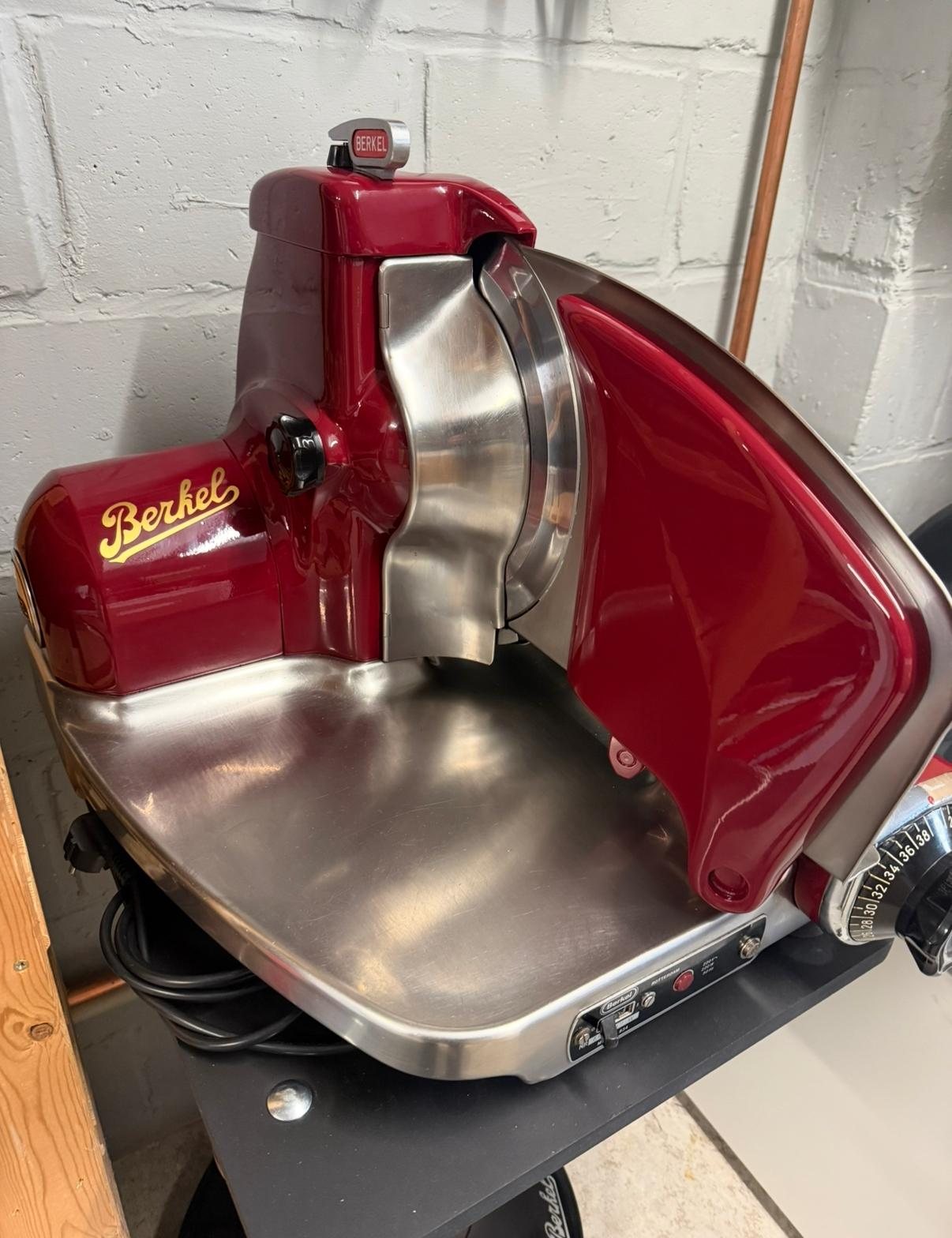 Gerestaureerde bordeauxrode elektrische Berkel snijmachine met gouden Berkel-logo